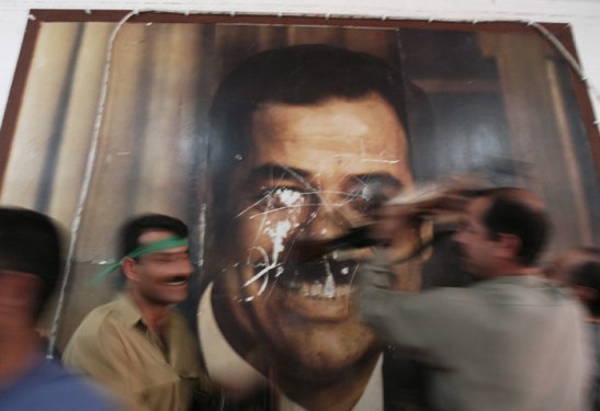 Hours after the fall of Kirkuk in 2003, Kurdish Peshmerga soldiers deface a poster of Saddam Hussein in a government building. Lynsey Addario/Getty Images Reportage